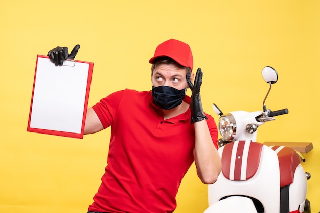 Vorderansicht männlicher Kurier in schwarzer Maske mit Dateinotiz auf gelbem Uniformjob Covid Delivery Pandemie Service Virus