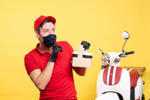Vorderansicht männlicher Kurier in schwarzer Maske mit Kaffeetassen auf gelbem Arbeitervirus-Kovid-Service-Arbeitsauftrag