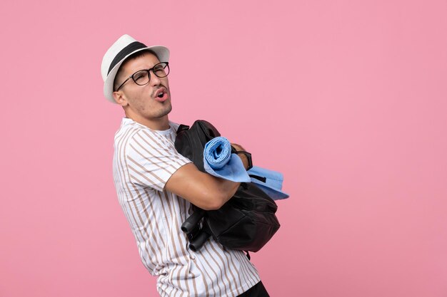 Vorderansicht männlicher Tourist, der seinen Rucksack auf rosa Wandemotionsfarbe Tourist hält