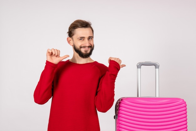 Vorderansicht männlicher Tourist mit rosa Tasche auf weißer Wand