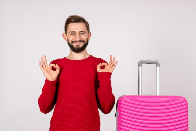 Vorderansicht männlicher Tourist mit rosa Tasche auf weißer Wand