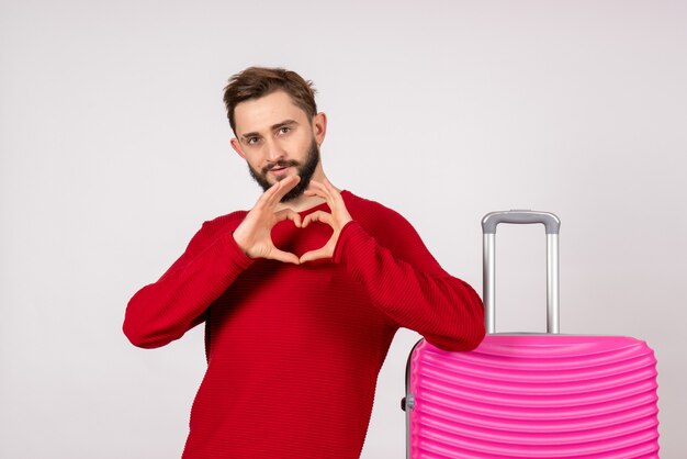 Vorderansicht männlicher Tourist mit rosa Tasche auf weißer Wand