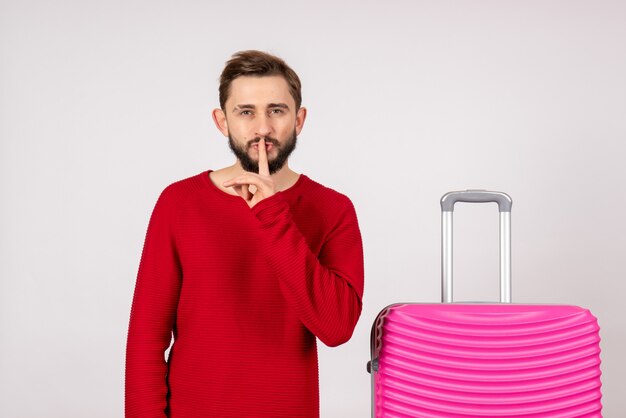 Vorderansicht männlicher Tourist mit rosa Tasche, der bittet, auf weißer Wand zu schweigen?