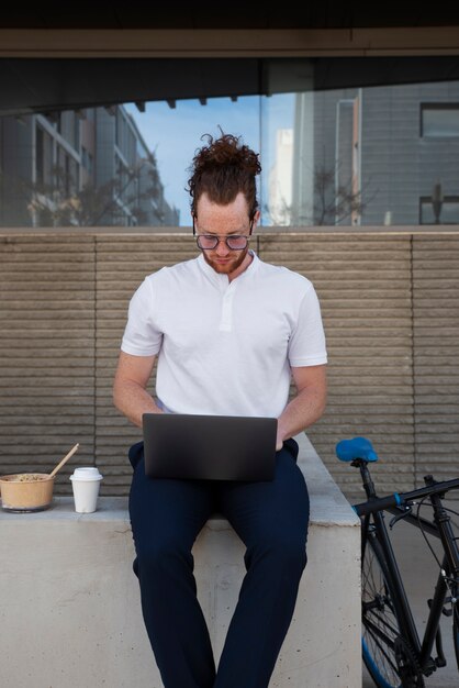 Vorderansicht Mann, der draußen am Laptop arbeitet