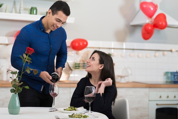 Kostenloses Foto vorderansicht mann, der wein in ein glas für seine frau gießt