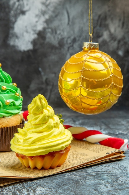 Vorderansicht Mini bunte Cupcakes Weihnachtsbaumkugel Weihnachtsbonbons auf Zeitung im Dunkeln