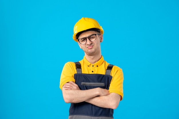 Vorderansicht missfiel männlicher Arbeiter in gelber Uniform auf Blau