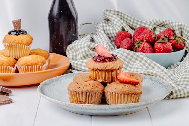 Vorderansicht Muffins mit Erdbeeren und Muffins mit Schokolade auf Tellern mit Erdbeeren