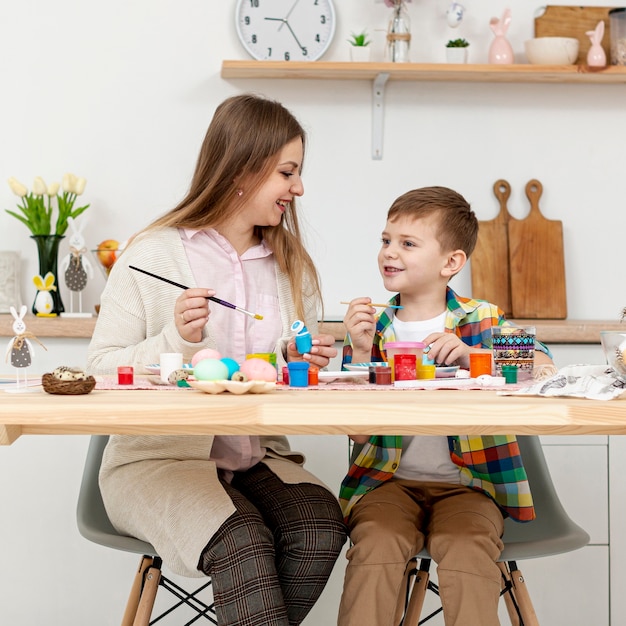 Vorderansicht Mutter und Sohn malen zusammen Eier für Ostern