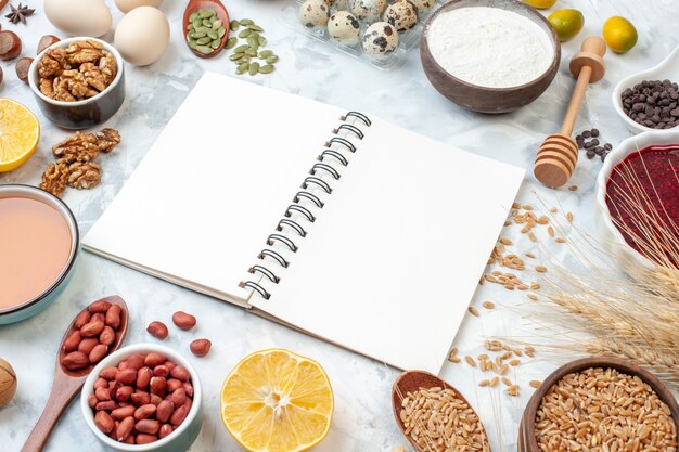 Vorderansicht offener Notizblock mit Gelee-Eiern verschiedenen Nüssen und Samen auf weißem Hintergrund Teigfarbe Nusskuchen süße Torte Herz Foto Zucker