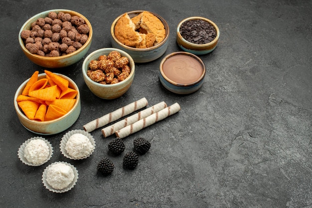 Vorderansicht orange cips mit süßen Nüssen und Schokoladenflocken auf einem dunkelgrauen Hintergrund Mahlzeit Snack Frühstück Nuss