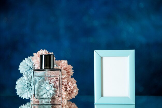 Vorderansicht Parfümflasche kleine blaue Bilderrahmen Blumen auf dunkelblauem Hintergrund Freiraum
