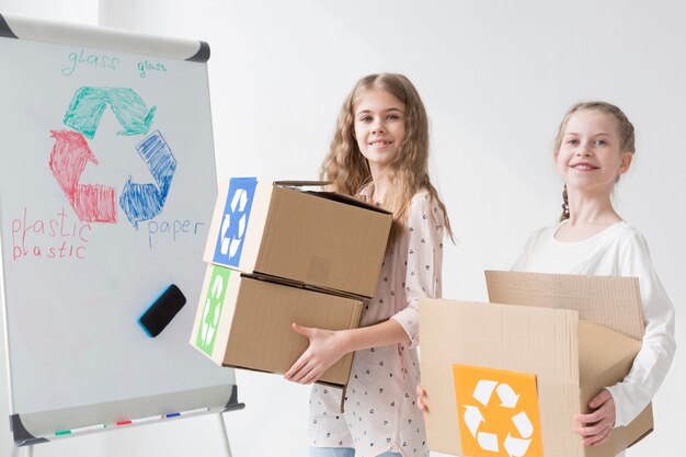 Vorderansicht positive junge Mädchen, die Recyclingboxen halten