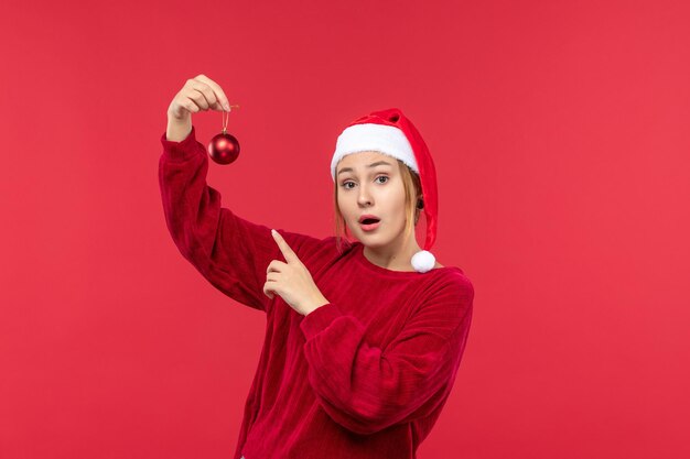 Kostenloses Foto vorderansicht regelmäßige weibliche halten weihnachtsspielzeug auf rotem boden weihnachtsrot urlaub