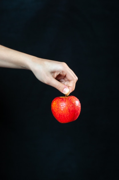 Vorderansicht reifer roter Apfel in der Hand auf dunkler Oberfläche