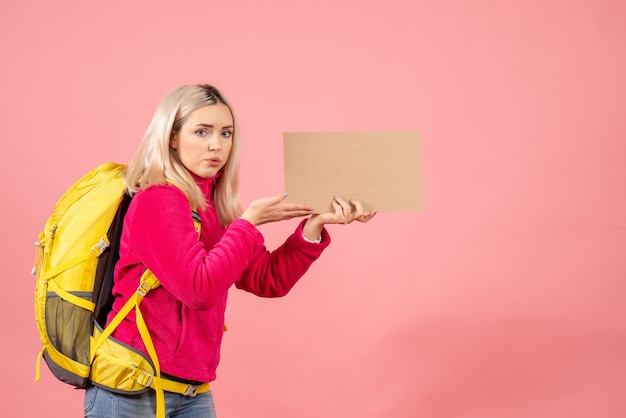 Kostenloses Foto vorderansicht reisende frau mit gelbem rucksack, der pappe hält