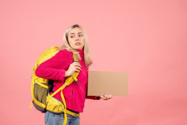 Vorderansicht reisende Frau mit Rucksack, der Pappe hält