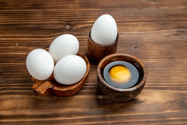 Vorderansicht rohe Eier ganze Produkte auf brauner Holzoberfläche Ei Essen Mahlzeit Frühstück Rührei