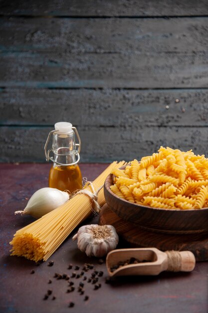 Vorderansicht rohe italienische Nudeln mit Zwiebeln auf dunklem Raum