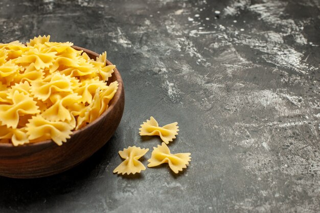 Vorderansicht rohe italienische Pasta innerhalb des Tellers auf dunkelgrauem Farbfotomehlteig viele Lebensmittelfreiraum