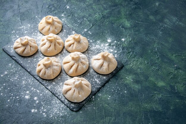 Vorderansicht rohe kleine Knödel mit Fleisch innen auf dunklem Hintergrundfarbgericht rohe Kochmahlzeitküche Teigfleischmehl