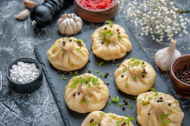 Vorderansicht rohe kleine Knödel mit Tomatensauce auf hellgrauem Tisch, der Abendessen Fleischgericht Teigküche Mahlzeit Kuchen kocht