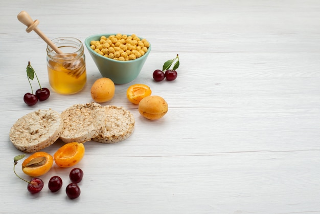 Vorderansicht rohes Getreide innerhalb Platte mit Crackerfrüchten und Honig auf weißem, Milchmilchmolkereifrühstück trinken