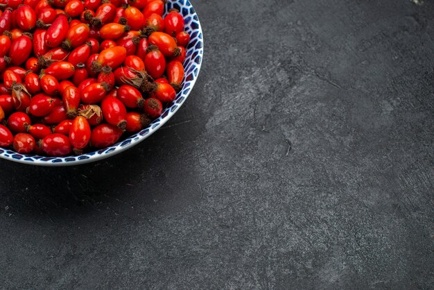 Vorderansicht rote Früchte reife und saure Beeren innerhalb Platte auf dem grauen Schreibtisch Früchte Beerenfarbe Vitamin Baum Pflanze
