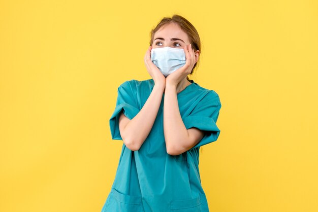 Vorderansicht Ärztin aufgeregt auf gelbem Hintergrund Krankenhausgesundheit Covidpandemie