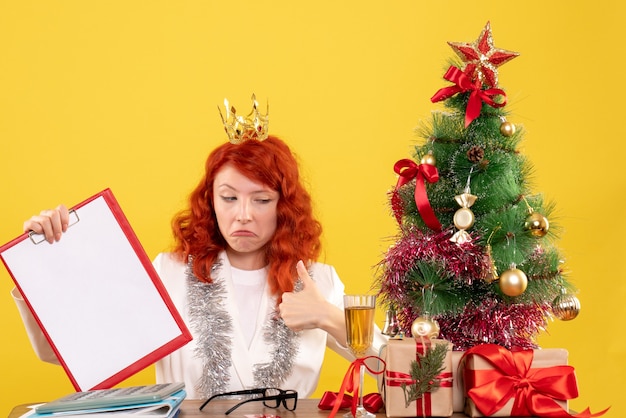 Vorderansicht Ärztin, die Aktennotiz um Weihnachtsbaum und Geschenke hält