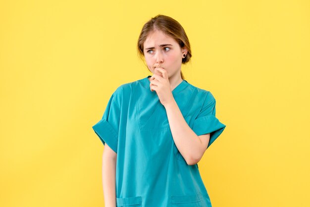 Vorderansicht Ärztin, die auf einem gelben Hintergrundmedizinergesundheits-Emotionskrankenhaus denkt