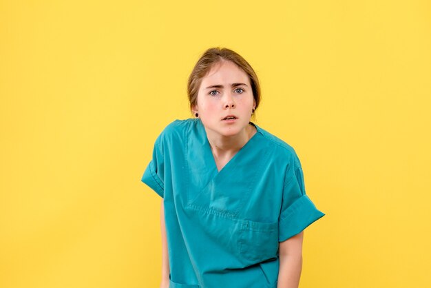 Vorderansicht Ärztin, die gerade auf gelbe Hintergrundkrankenhaus-Gesundheitsgesundheitsemotion schaut
