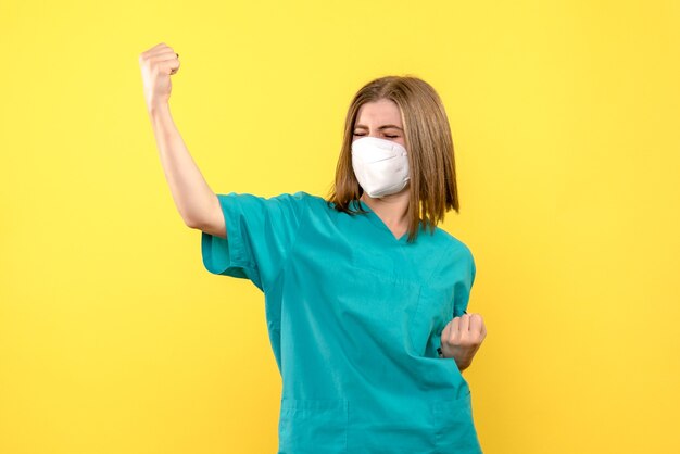 Vorderansicht-Ärztin, die Maske auf gelbem Raum trägt