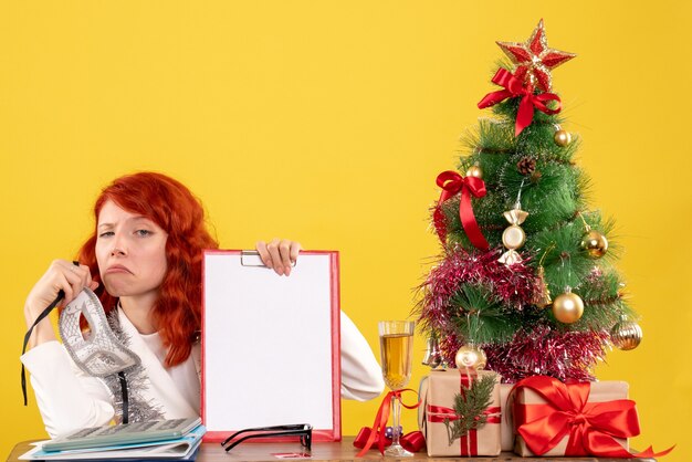 Vorderansicht-Ärztin, die Maske um Weihnachtsbaum und Geschenke hält