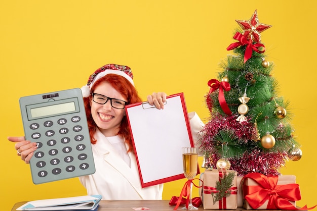 Vorderansicht Ärztin, die Rechner um Weihnachtsgeschenke und Baum hält