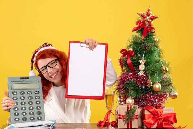 Vorderansicht Ärztin, die Rechner um Weihnachtsgeschenke und Baum hält