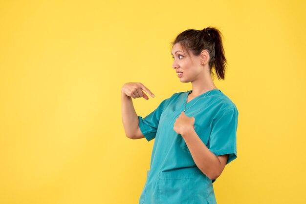 Vorderansicht-Ärztin im medizinischen Hemd auf gelbem Hintergrund