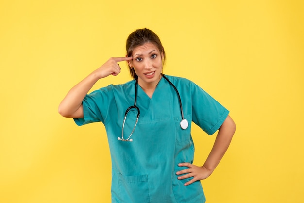 Vorderansicht-Ärztin im medizinischen Hemd auf gelbem Hintergrund
