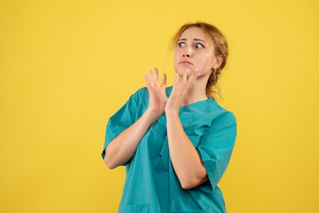 Vorderansicht Ärztin im medizinischen Hemd auf gelbem Schreibtisch covid-19 Krankenschwesterfarbgesundheitsmediziner