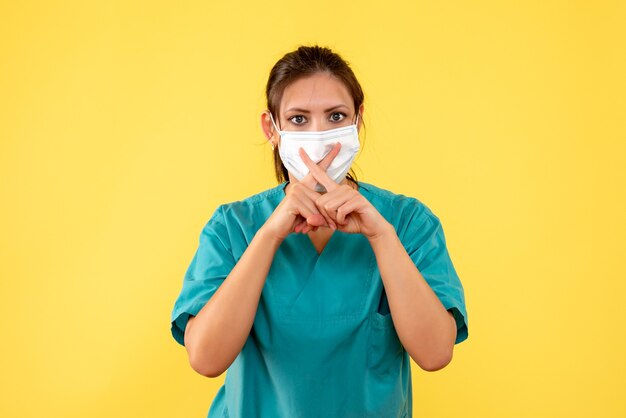 Vorderansicht-Ärztin im medizinischen Hemd und in der Maske auf gelbem Hintergrund