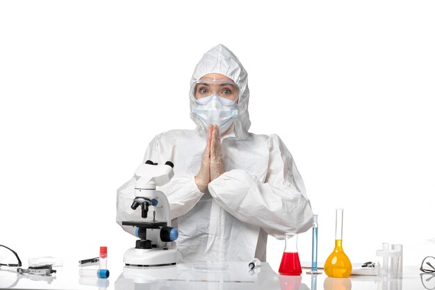 Vorderansicht Ärztin im Schutzanzug mit Maske wegen Covid sitzt gerade auf weißem Hintergrund Virus Pandemie Splash Covid-