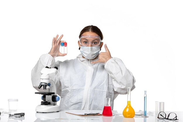 Vorderansicht Ärztin im Schutzanzug und mit Maske, die leere Flaschen auf weißem Hintergrund Covid Pandemic Virus Coronavirus hält