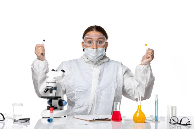 Vorderansicht Ärztin im Schutzanzug und mit Maske, die Proben auf weißem Hintergrundmedizingesundheitspandemievirus-Coronavirus hält