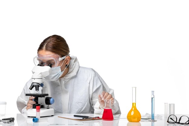 Vorderansicht Ärztin im Schutzanzug und mit Maske unter Verwendung eines Mikroskops auf weißem Hintergrund Medizin Covid-Health-Pandemie-Virus