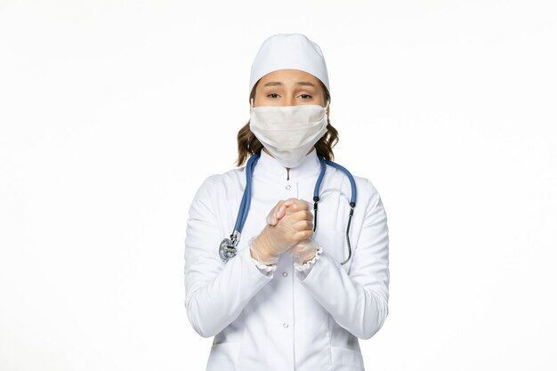 Vorderansicht Ärztin im weißen medizinischen Anzug, der Maske wegen Coronavirus auf weißer Schreibtischpandemie-Virusisolation trägt