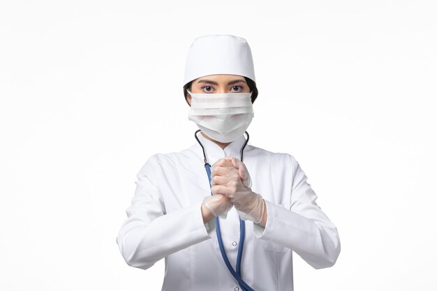 Vorderansicht Ärztin im weißen sterilen medizinischen Anzug mit Maske aufgrund des Covid-on-White-Wall-Krankheit-Covid-Pandemie-Virus