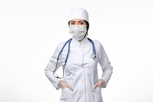 Vorderansicht Ärztin im weißen sterilen medizinischen Anzug und mit Maske aufgrund von Covid-Posing auf der White-Wall-Disease-Virus-Covid-Pandemie