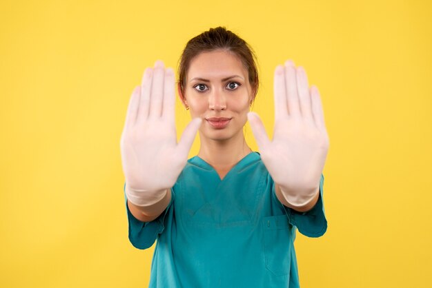 Vorderansicht Ärztin in Handschuhen auf gelbem Hintergrund