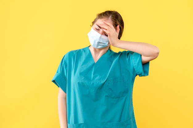 Vorderansicht Ärztin in Maske auf gelbem Hintergrund Gesundheitskrankenhaus Covid Pandemie gestresst