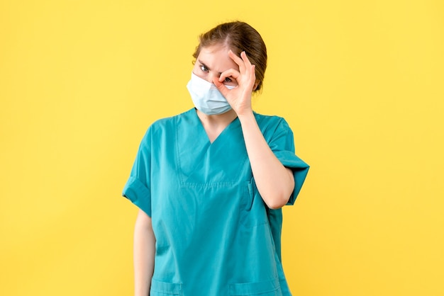 Vorderansicht Ärztin in Maske auf gelbem Hintergrund Gesundheitskrankenhaus Covid Pandemie